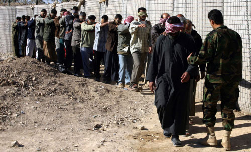 جندي عراقي يقود مجموعة من المعتقلين في بعقوبة أمس (أ ف ب)