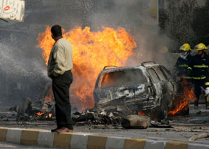عراقي يقف أمام حريق سيارة منفجرة في بغداد أمس (أ ب)
