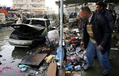 عراقيّون يتفقّدون مسرح انفجار سيّارة في بغداد أمس (رويترز)