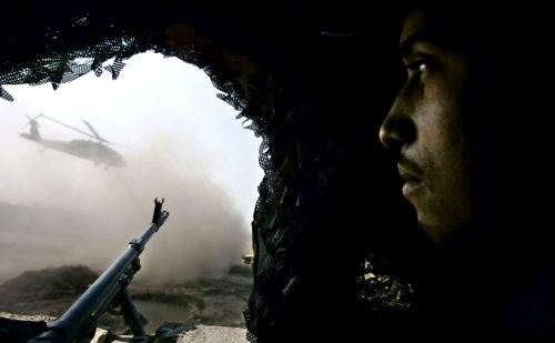 شرطي عراقي يراقب إقلاع مروحيّة أميركيّة في قاعدة عسكريّة جنوب شرق بغداد أمس (رويترز)