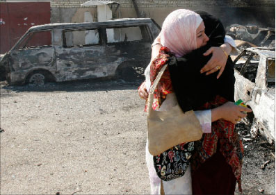عراقيّتان تواسيان بعضهما بعد تفجير سيّارة في بغداد أمس (محمود محمود - رويترز)