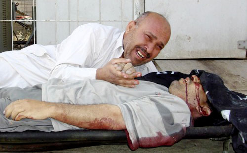 عراقي ينتحب قرب جثمان أخيه الذي قضى برصاص مسلّحين في بعقوبة أمس (حلمي الزاوي - رويترز)