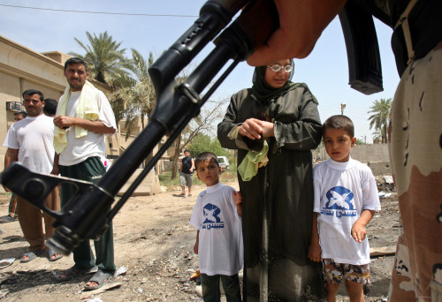 عراقية تعيد أولادها من المدرسة وأمامهم جندي أميركي غرب بغداد أمس (خالد محمد- أ ب)