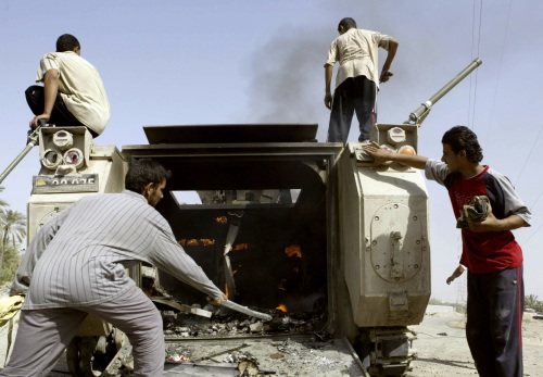 عراقيون حول الدبابة الدنماركية المحترقة في البصرة أمس (عاطف حسن - رويترز)