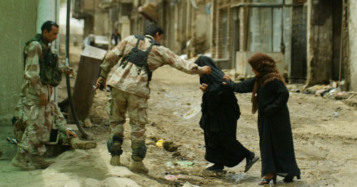 جندي عراقي يساعد عراقيتين على السير في موقع التفجير في بغداد أمس (على يوسف - أ ف ب)