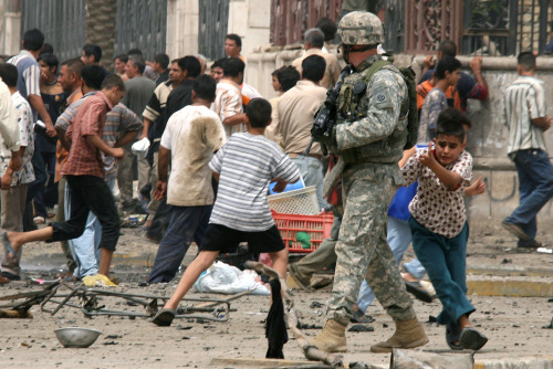 جندي أميركي وسط هلع العراقيين بعد دقائق من التفجير الانتحاري في بغداد أمس (خليل محمد - أ ب)