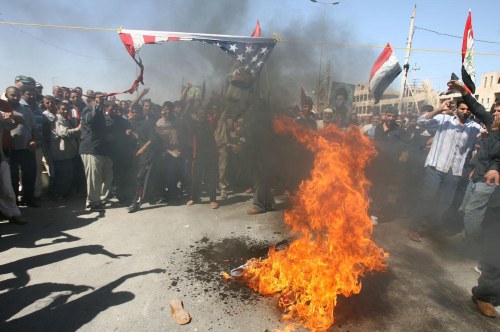 عراقيون يحرقون العلم الأميركي احتجاجاً على استهداف مرقد سامرّاء في مدينة الصدر أمس (كريم رحيم - رويترز)