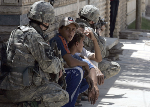 جنديان أميركيان وبينهما مدنيون عراقيون بعد الهجوم بالصواريخ في الدورة جنوب بغداد أمس (بيتروس جياناكوريس - أ