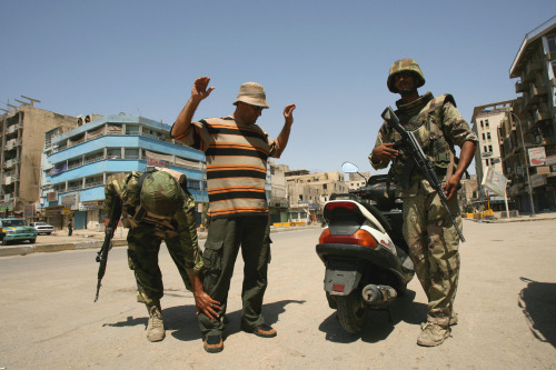 جندي عراقي يفتّش دراجاً خلال حظر التجوّل في بغداد أمس (خالد محمد - أ ب)