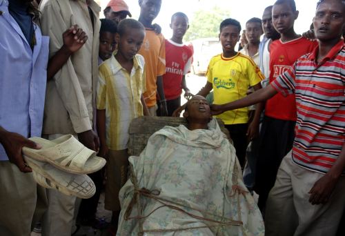صوماليون حول جثّة شاب قتله مسلّح في مقديشو مطلع الأسبوع (رويترز)