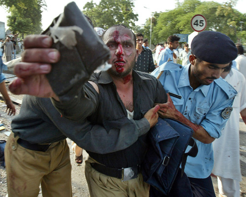 الشرطة الباكستانية تساعد جريحاً بعد انفجار في اسلام أباد أمس (عامر قريشي - أ ف ب)