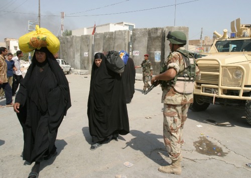 عراقيات يسرن بمحاذاة جندي عراقي في كربلاء أمس (مشتاق محمد - رويترز)