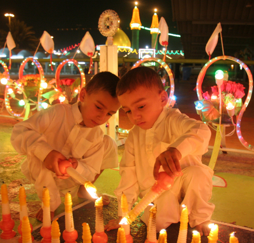 طفلان عراقيان يضيئان الشموع في كربلاء أول من أمس (غسان الياسري - أ ب)