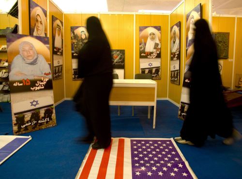 إيرانيتان تدوسان علماً أميركياً خلال معرض في طهران أمس (مرتضى نيكوبازل ــ رويترز)