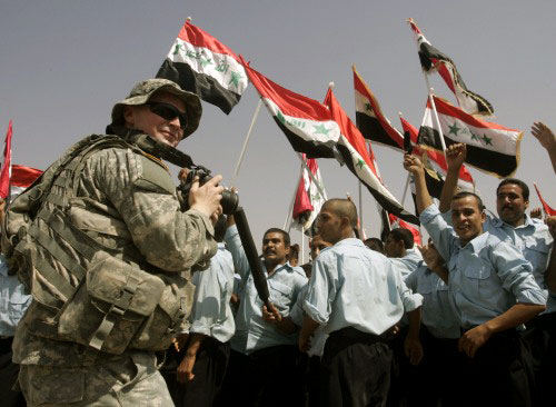 جندي أميركي يصوّر أفراداً من الشرطة العراقية خلال حفل تخرّجهم في بغداد أمس (محمد أمين ـ رويترز)