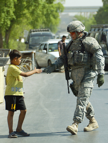 فتى عراقي يصافح جندياً أميركياً في بغداد أمس (علي يوسف - أ ف ب)