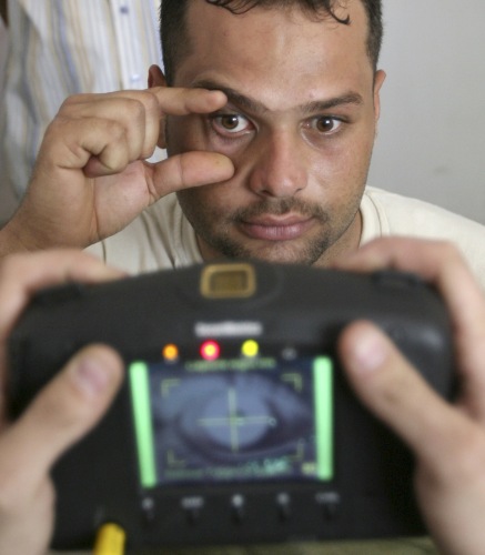 متطوّع في الشرطة العراقية يخضع لفحص «بصمات العين» في بغداد أمس (إريك دي كاسترو ـ رويترز)
