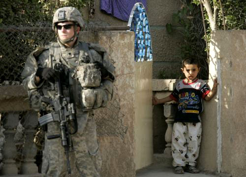طفل عراقي يراقب جندياً للاحتلال الأميركي في الظفرانية في بغداد أمس (ف. بنش - رويترز)
