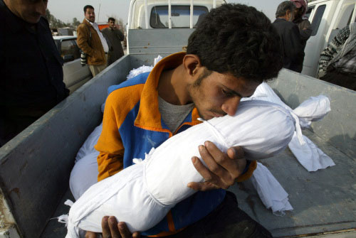 عراقي يحضن جثّة طفل قتل خلال مجزرة لـ«القاعدة» في النجف أمس (علاء المرجاني ــ أ ب)