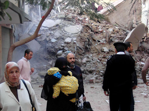 مصريّون عند موقع انهيار المبنى في الاسكندريّة أمس (أ ب)