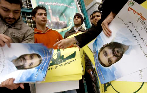 إيرانيّون يوزّعون صور مغنيّة في طهران أمس (رويترز)