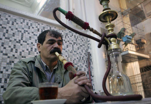 إيراني يدخّن النرجيلة في أحد مقاهي طهران أمس (بهروز مهري ـ أ ف ب)