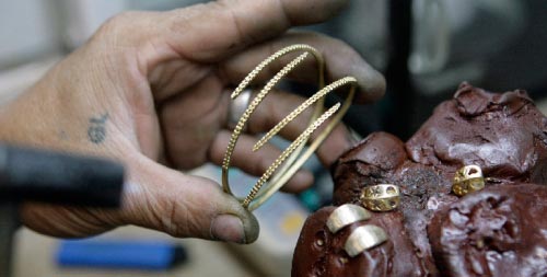 موظّف فيليبيني يرتّب قطع الذهب في متجر في مانيلا أمس (جون جافيلانا ـ رويترز)