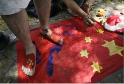 تيبتيّون يدوسون العلم الصيني في نيو دلهي أمس (مصطفى قريشي ـ أ ب)