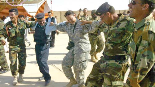 عناصر من الشرطة العراقيّة يراقصون ضابطة أميركيّة احتفالاً بالإفراج عن معتقلين في كركوك أول من أمس (أ ف ب)