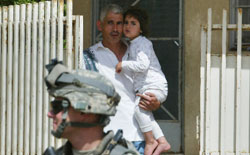 عراقي يحمل طفلته خلف جندي أميركي في الموصل الأسبوع الماضي (علي يوسف ــ أ ف ب)