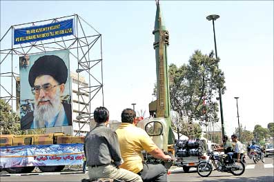 مجسم لصاروخ «شهاب 2» قرب صورة لمرشد الجهورية الايرانية اية الله علي خامنئي في احد شوارع طهران أمس (أ ف ب)