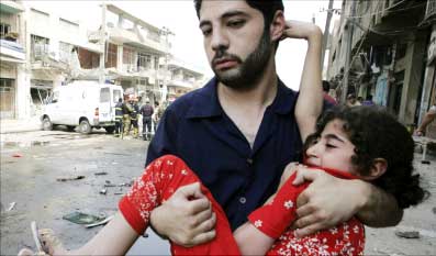 عراقي يحمل طفلة اصيبت في انفجار قنبلة في بغداد أمس (رويترز)