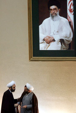 رجلا دين إيرانيان تحت صورة لمرشد الجمهورية علي خامنئي في البرلمان أمس (أف ب)