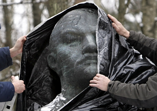 عمّال ليتوانيّون يغطّون تمثالاً لفلاديمير لينين في منتزه في دروسكينينكا الشهر الماضي (أ ب)