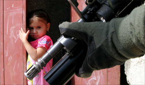 طفلة عراقيّة تنظر إلى سلاح جنديّ أميركي في مدينة الصدر في بغداد أمس (أ ب)