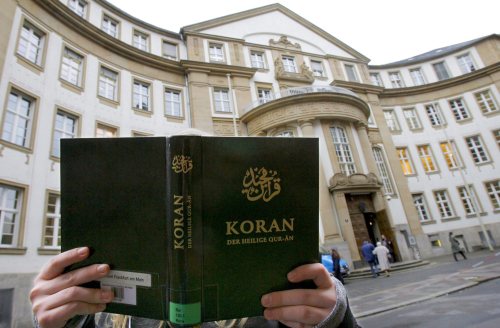 مسلمة تحمل نسخة من القرآن أمام محكمة في فرانكفورت أوّل من أمس (إي بي أي)