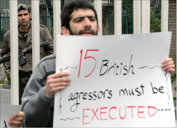 طالب إيراني يرفع عبارة «الموت للبريطانيّين المعتدين» خلال احتجاج في طهران أمس (رويترز)