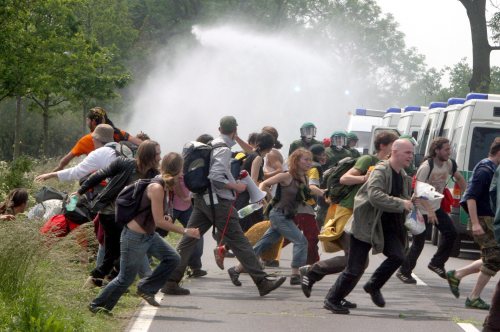 متظاهرون يهربون من خراطيم مياه الشرطة الألمانية أمس (كاي نيتفيلد - إي بي أي)