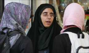شرطية تتحدّث إلى طالبتين بشأن لباسهما في طهران أمس (بهروز مهري - أ ف ب)