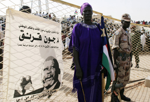 جندي وامرأة سودانيان أمام صورة لجون قرنق في الخرطوم أول من أمس (عصام الحاج - أ ف ب)