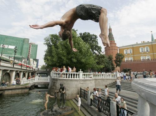 فتى يقفز في المياه بالقرب من الكرملين في موسكو أمس (سرجاي كاربوخين - رويترز)