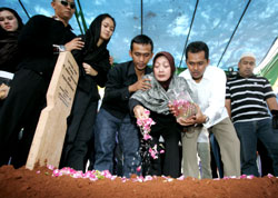 أفراد عائلة ربّان الطائرة التي تحطّمت ينثرون وروداً على قبره في جاكارتا أمس (أشمد إبراهيم ـ أ ب)