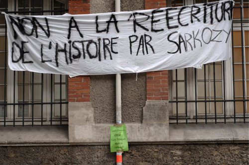 لافتة احتجاج على «إعادة ساركوزي كتابة التاريخ» على حائط إحدى المدارس في باريس أمس (يوان فالات ـ إي بي آي)