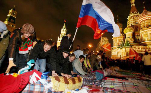 ناشطون في حركة «ناشي» الموالية للكرملين يعرضون قماشاً مرقعاً رمزاً للصداقة بين الشعوب في الساحة الحمراء في موسكو أوّل الشهر الجاري (إي بي أي)