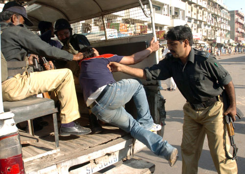 شرطيان باكستانيان يعتقلان أحد أنصار المعارضة في كراتشي أمس (رزوان تاباسوم ـ أ ف ب)