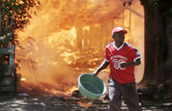 كيني يحاول إطفاء منزل أحرقته أعمال العنف في نيروبي أمس (توماس موكويا ـ رويترز)