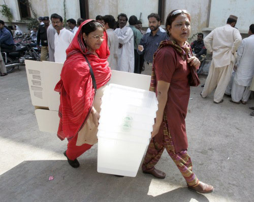 باكستانيّتان تحملان المعدّات اللازمة لعمليّة الاقتراع في حيدر أباد أمس (أكرم شهيد - رويترز)