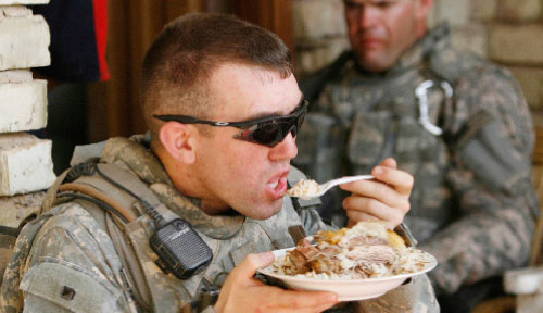 جندي أميركي يتناول طبقاً عراقيّاً جنوبي العراق (محمود رؤوف محمود ـــ رويترز)