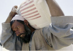 أفغاني يحمل كيساً من الطحين من ضمن مساعدات برنامج الغذاء العالمي في كابول أمس (أ ب)