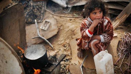 أمام منزل أسرتها المهدّم في جباليا شمالي غزة، تنتظر الطفلة تعقّم المياه على أحر من الجمر لتشرب (أ.ب ــ أنجا نيدرينغهاوس ) 